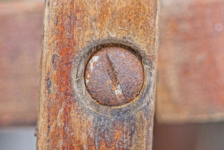 one brown iron rusty bolt with nut in wood plank in constructionの写真素材