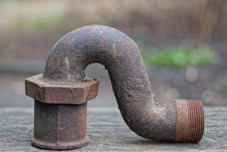 sewerage detail from a piece of brown rusty old iron pipe with a thread and a nut lies on a gray...