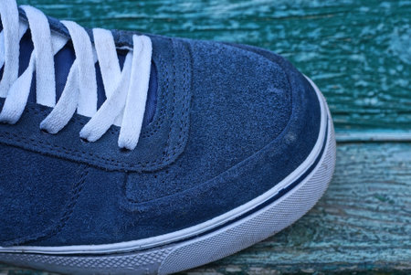 part of a blue suede sneaker with a white lace on a green tableの写真素材