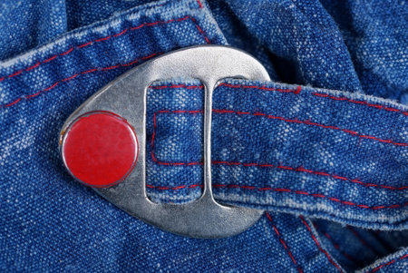 one gray metal fastener with red iron rivet on a blue tulle fabric harness on clothesの写真素材