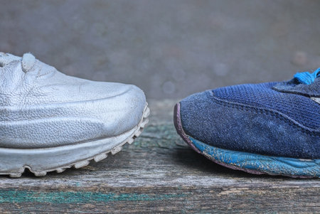 two sneakers made of gray leather and blue suede stand on a gray table in the street