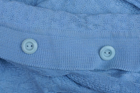 two round plastic buttons on a blue woolen garment fabric