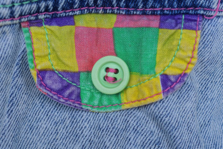 one green plastic button on the colored pocket of the blue fabric of the garment