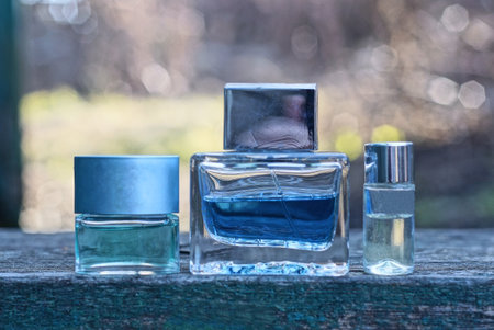 three small glass bottles with colored perfume stand on a gray table in the streetの写真素材