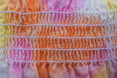 texture from a piece of colored crumpled fabric with white seams on clothes