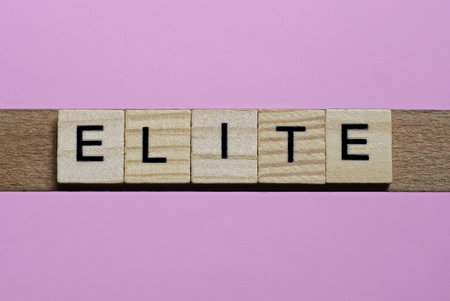 word elite from small gray wooden letters lies on a pink backgroundの写真素材
