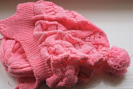 one pink winter woolen hat with a fluffy pompom lies on a white tableの写真素材