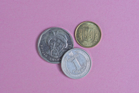 a set of three Ukrainian coins lie on a pink tableの写真素材