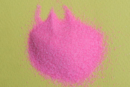 one small pile of decorative pink sand on a yellow tableの写真素材