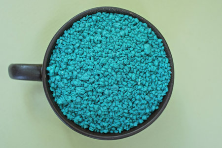 blue small decorative stones in a brown ceramic cup stands on a gray green tableの写真素材