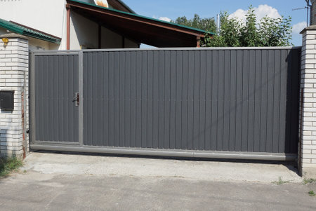 black iron gate and closed metal door on a white brick fence wall in a rural street