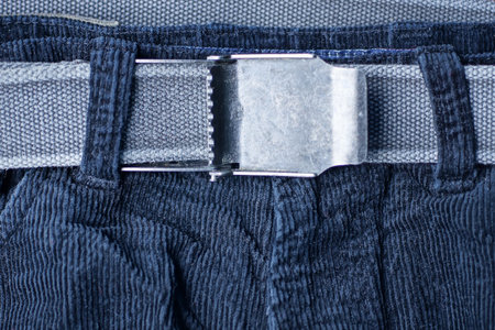 gray belt with an open metal buckle on the black fabric of trousersの写真素材