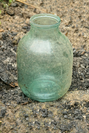 one large empty dirty glass jar stands on the gray ground in the streetの写真素材