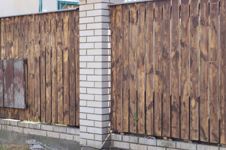 brown fence wall made of wooden boards and white bricks in the streetの写真素材