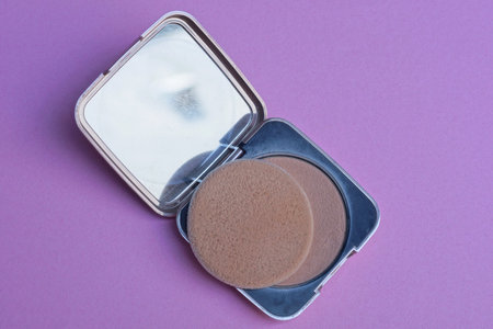 one small open plastic black box with brown powder and a round napkin lies on a pink tableの写真素材