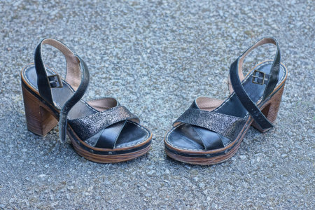 two black leather summer sandal shoes stand on gray asphalt in the street