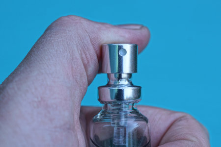 one gray bottle in fingers of hand on a blue background