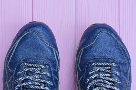 two blue sports sneakers made of fleather stand on a pink wooden tableの写真素材