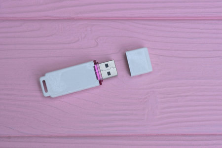 one small white plastic closed mobile flash drive lies on a pink wooden tableの写真素材
