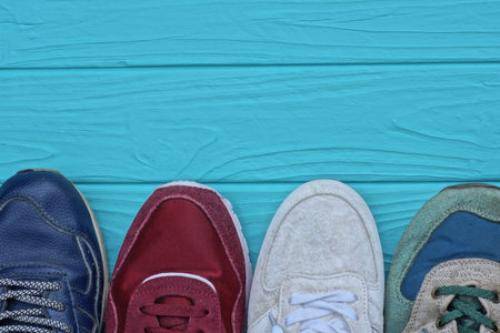 a row of different four sports colored sneakers stand on a blue wooden tableの写真素材