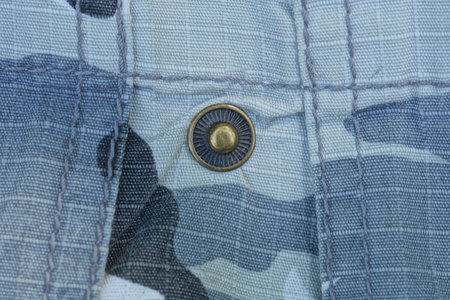 one small brown metal rivet button on gray black fabric on clothes