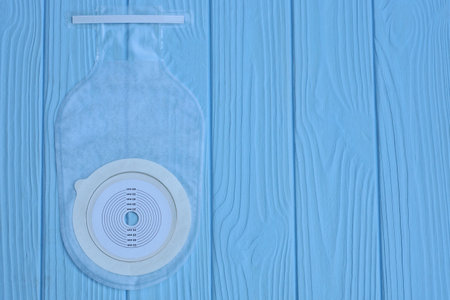 one white plastic medical colostomy bag lies on a blue wooden table