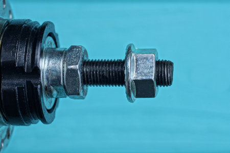 part of a bicycle hub with a black iron screw and gray nuts on a blue backgroundの写真素材