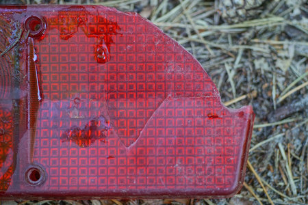 one piece of a broken red dirty plastic car headlight lies on the gray ground in the streetの写真素材