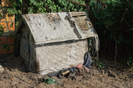 one old wooden doghouse upholstered in gray fabric stands on the ground in the streetの写真素材