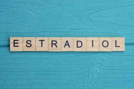 word estradiol made of small gray wooden letters on a green blue wood backgroundの写真素材