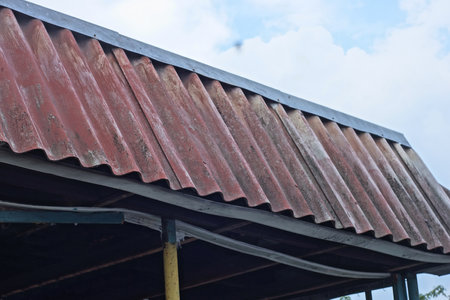 part of the attic under a brown slate roof on a rural street against the sky