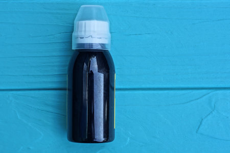 one brown small glass medical bottle with a white cap lies on a blue wooden tableの写真素材