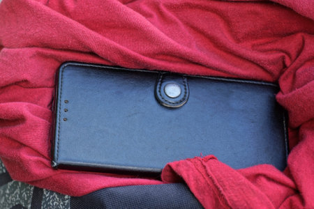 one black closed leather smartphone case lies on a red crumpled fabric