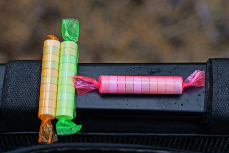 three long candies in colored packaging lie on a thin black table on the street