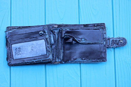 one old open brown leather wallet lies on a blue wooden table