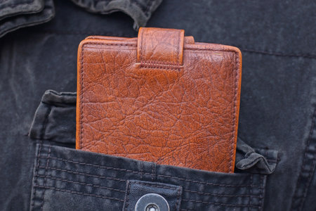 one old red leather wallet lies in the pocket of a black jacketの写真素材