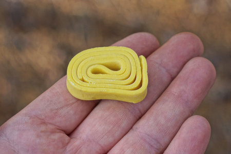 one yellow chewing gum candies lies on the palm of the hand