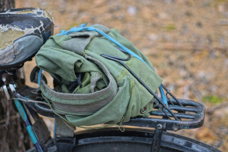one empty green backpack lies on a black bicycle trunk on the streetの写真素材