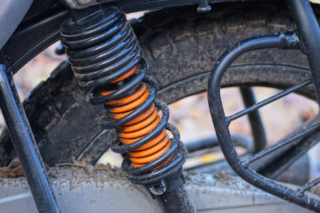part of a sports motorcycle with a red wheel and a black orange metal spring on the streetの写真素材