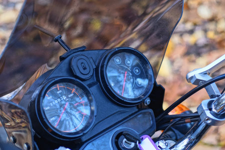 part of a black motorcycle with round speedometers and steering wheel on the street