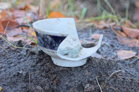 one dirty white blue broken plate lies on the gray ground in the streetの写真素材