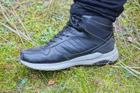 oga man in a black leather sneaker stands on green moss on the street in nature