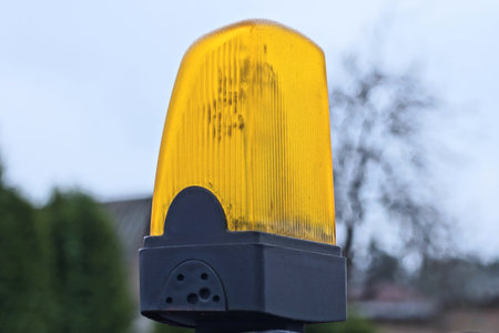 one yellow black large glass yellow signal light stands on a brown wooden fence wall on the street