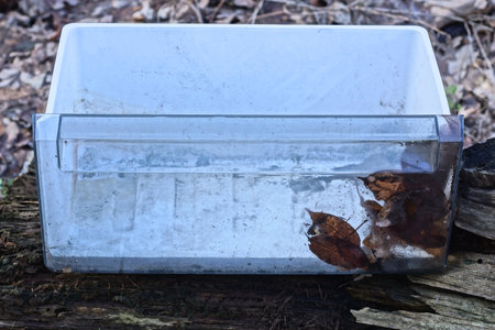 one white old dirty plastic box stands on a gray table on the streetの写真素材