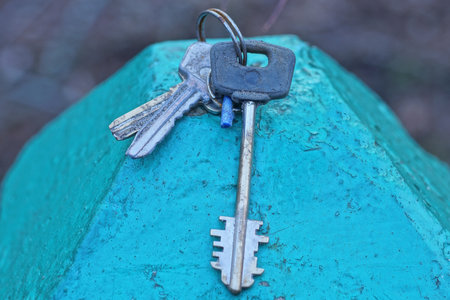 three door keys on a metal ring lie on a green tableの写真素材