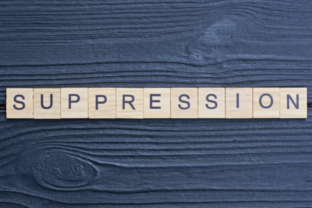 text the word suppression from brown wooden small letters on a blue wooden surface
