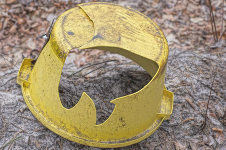 one old yellow broken plastic bowl with a big hole and cracks lies in the fallen brown foliage on...
