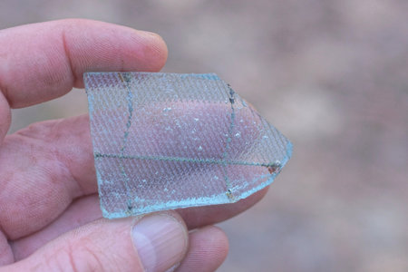 hand holding a piece of white glass with a pattern on the street