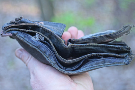 hand holding one empty black leather wallet on the street on a gray background