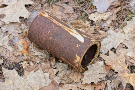 one large brown rusty iron tin can stand on gray dry leaves and earth on the street